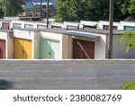 Small photo of A large "garage yard" with old brick garages. In the background, a historic multi-family house.Concrete garages with steel doors and roofs covered with felt. Garage space located among rich greenery .