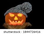Carved halloween pumpkin with scarf and knitted hat isolated on a black background