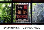 Small photo of Bandung, Indonesia - July 7, 2022: Proverb about life written on retro vintage metal sign wall decoration says "enjoy the little things" usually for restaurant, bar, and cafe decoration.