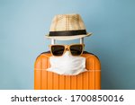 Travel restriction abstract made of tourist in form of of luggage with face mask, sunglasses and hat.