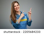 Smiling woman in blue overalls pointing up with two fingers. Isolated female portrait in builder worker uniform.