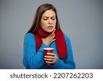 Sick woman with cold fever touching her neck, sore throat, holding red mug. Female person isolated portrait, looking away down.