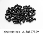 Small photo of Black vitamins, pills in the shape of a ellipse on a white background. For pharmacies, backgrounds, medicine, vitamins, healthcare workers