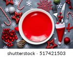 Christmas table place setting with empty red plate, cutlery in santa hat with festive decorations bauble snowflake star bow ball pinecone berry candy cane. Christmas Xmas New Year holiday background