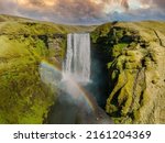 Famous Skogafoss waterfall with a rainbow. Dramatic Scenery of Iceland during sunset. Majestic Skogafoss Waterfall in countryside with colorful sky aerial scenic view.