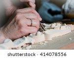 Artisan woodcarver creates a furniture ornament. Woodcarver's hands, chisels, tools, wood-carved ornament.