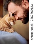 Small photo of Muzzle of a red cat and a man's face. Close-up of handsome young beard man and tabby cat - two profiles. Pets and humans friendship, love and trust concept