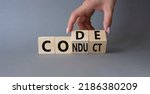 Small photo of Code of conduct symbol. Businessman hand Turnes cubes and changes word Conduct to Code. Beautiful grey background. Business and Code of conduct concept. Copy space