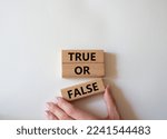 Small photo of True or false symbol. Wooden blocks with words True or false. Beautiful white background. Businessman hand. Businessman hand. Business concept and True or false. Copy space.