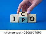 Small photo of ICO and IPO symbol. Businessman hand turns wooden cubes with words ICO - initial coin offering and IPO - initial public offering. Beautiful blue background. Business concept. Copy space
