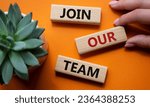 Small photo of Join our team symbol. Wooden blocks with words Join our team. Beautiful orange background with succulent plant. Businessman hand. Business and Join our team concept. Copy space.