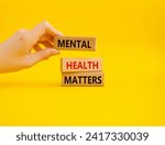 Small photo of Mental Health Matters symbol. Concept words Mental Health Matters on wooden blocks. Beautiful yellow background. Doctor hand. Healthcare and Mental Health Matters concept. Copy space.