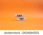 Small photo of Just try symbol. Concept words Just try on wooden blocks. Beautiful orange background. Business and Just Try concept. Copy space.
