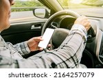 Small photo of Man using his phone while driving, Person holding the cell phone and with the other hand the steering wheel, Concept of irresponsible driving, Distracted driver using the cell phone while driving