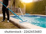 Small photo of Hands of worker cleaning a swimming pool with special brush, Maintenance person cleaning swimming pool with broom. Swimming pool cleaning with brush