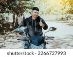 Small photo of Biker on his motorbike holding safety helmet with thumb up. Concept of Smiling motorcycle cyclist holding safety helmet, Biker man giving thumb up while holding safety helmet