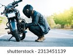 Small photo of Biker repairing motorcycle on the road. Motocyclist fixing the motorcycle on the road, Man checking his motorcycle on the road