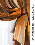 Small photo of Silk striped drape in rust, cream and sage green with ornate holdback. Close up detail of the fabric texture and colors of this luxurious window treatment.