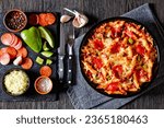Small photo of delicious Pizza Casserole of tender penne pasta, browned beef meat, pepperoni, olives, bell peppers, and cheese smothered in marinara sauce in dish on dark wood table with ingredients, flat lay