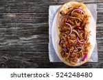 Barbeque Pulled Pork ciabatta open Sandwich with BBQ Sauce, red onion and chili pepper on parchment paper on oval plate, copyspace left, view from above