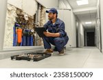 Small photo of Male plumber diagnoses pipes in water supply system before repairing and makes notes in clipboard