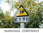 Chinese Warning sign of pedestrians crossing road ahead near school(前方学校means School Ahead)