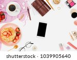 Beautiful flatlay arrangement with cup of coffee, hot waffles with cream and strawberries, smartphone with copyspace and beauty accessories: concept of busy morning breakfast, white background.