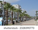 Small photo of Larnaca, CY - September 15th 2022 View down Larnaca, Finikoudes strip in the summer with people enjoying the beach and the love bus, sightseeing tour