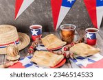 Small photo of Fiestas Patrias Chile September 18, Independence Day. Empanadas, Anticuchos, mote con huesillo, chicha or wine, Sombrero huaso chupallas of straw and emboque, on a wooden table with flag