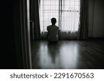 Alone man silhouette staring at the window closed with curtains in bedroom. Man stands at window alone