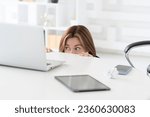 Small photo of Hysterical business woman hiding behind desktop and looking at laptop in the office. Business crisis and bankruptcy concept