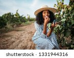 Young black woman eating a grape in a vineyard