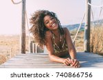 Beautiful young black woman lying down in a  wooden foot bridge at the beach 