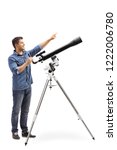 Small photo of Full length shot od a man standing next to a telescope and pointing up isolated on white background