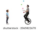 Small photo of Full length profile shot of a little boy looking at a mime juggling with balls and riding a unicycle isolated on white background