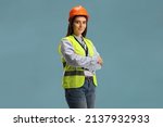 Young female site engineer with a safety vest and hardhat isolated on blue background