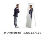 Full length profile shot of a young man getting ready and looking at a mirror isolated on white background