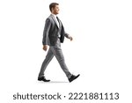 Small photo of Full length profile shot of a young professional man in a gray suit walking isolated on white background