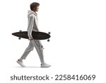 Full length profile shot of an african american guy carrying a longboard and walking isolated on white background    