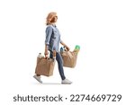 Small photo of Full length profile shot of a mature woman carrying grocery bags and walking isolated on white background