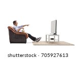Young man seated in an armchair watching television and laughing isolated on white background
