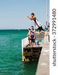 Small photo of MELBOURNE/AUSTRALIA - FEBRUARY 6: Youths jump off a jetty into the water, while others fish in Mordialloc, a coastal suburb of Melbourne, Australia in February.