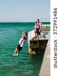 Small photo of MELBOURNE/AUSTRALIA - FEBRUARY 6: Youths jump off a jetty into the water, while others fish in Mordialloc, a coastal suburb of Melbourne, Australia in February.