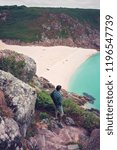 Small photo of Man looking over Porthcurno Beach, Pedn Vounder beach and Logan Rock seen from Minack Open Air Theatre; Cornwall; England; UK