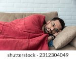 Small photo of Absolute solitude. Side view of a depressed unhappy sad man lying on the sofa and hugging a blanket while feeling lonely, sad and miserable. Depression mental health social issue