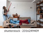 Young couple stares at the ceiling and yells because a neighbor upstairs is having a party with loud music or renovating an apartment and workers are drilling with heavy tools. Noise pollution concept