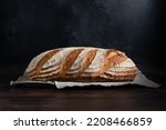 Sourdough bread. Freshly baked organic wheat bread on dark background,  with linen tablecloth. Side view.