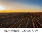 A tractor plowing his field and a field in a sunset view