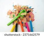 Small photo of Colorful pencil shavings with pencils and green shavings on a white background. Whole and broken lead pencils on white background. The rest of the pencil. Macro, pile of shavings