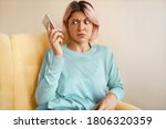 Small photo of Portrait of frowning young woman in blue sweatshirt holding mobile, dialing wrong number, having shocked look. Annoyed girl having unpleasant phone conversation. People and technology concept